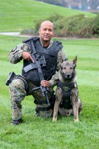 Police officer in bullet proof vest with rifle and a Belgian Malinois Police Dog